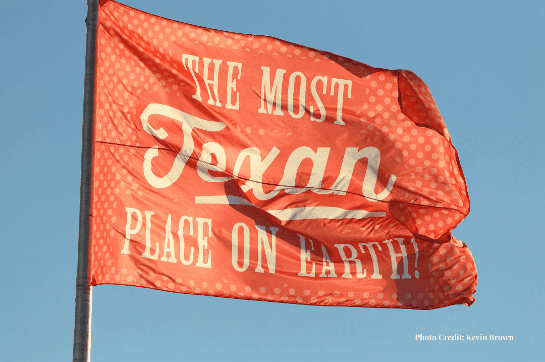 State Fair of Texas flag reading ‘The Most Texan Place on Earth’ against a blue sky.