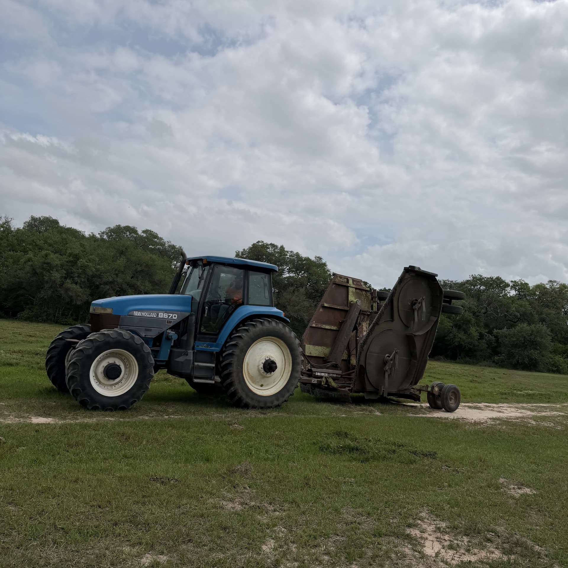 Tractor with pasture mower on Texas ranchland, demonstrating active agricultural land management