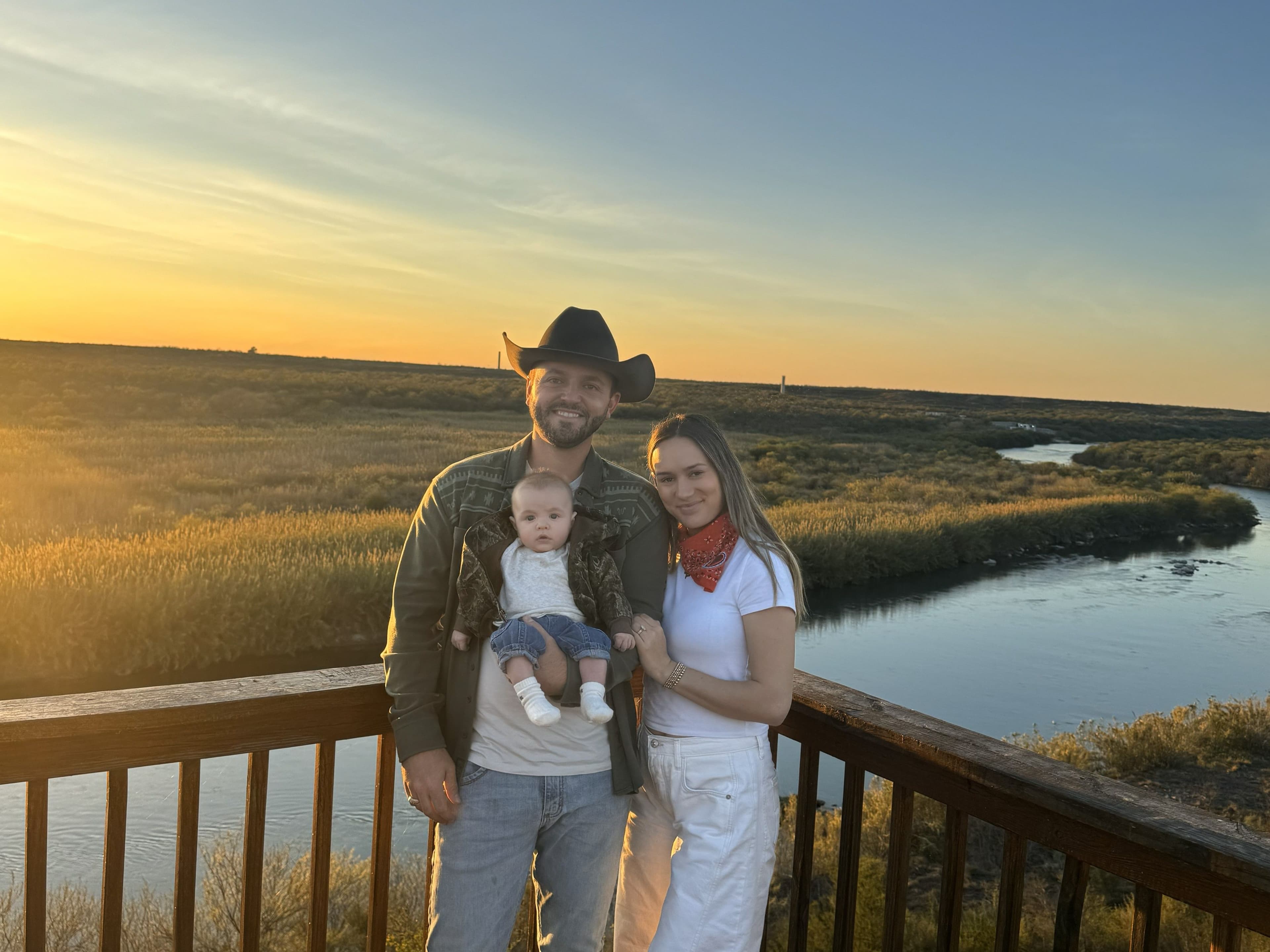 Brian Cook stands with his wife and child