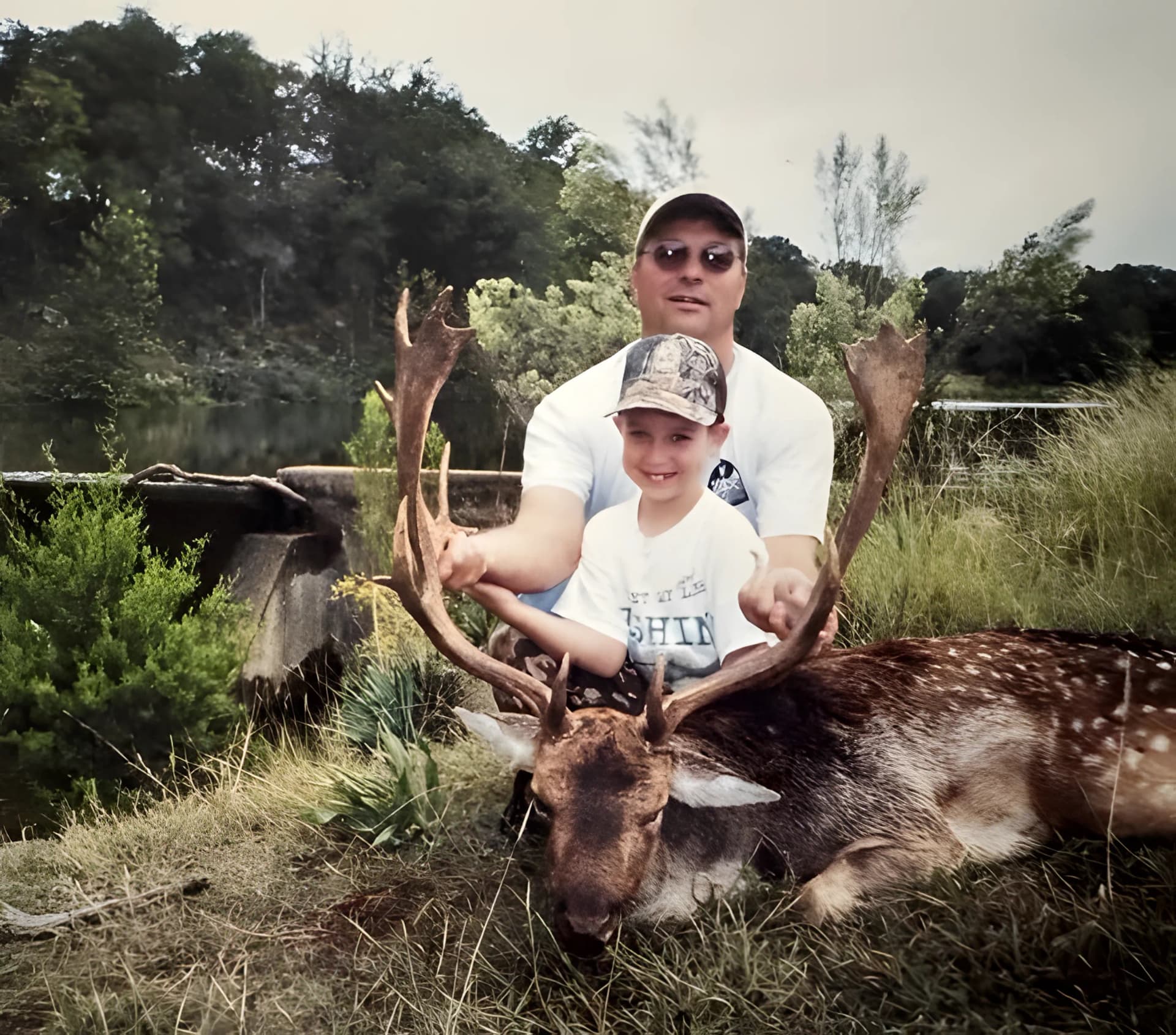 Father and son posing with a harvested buck during a Texas deer hunt, highlighting a shared hunting tradition