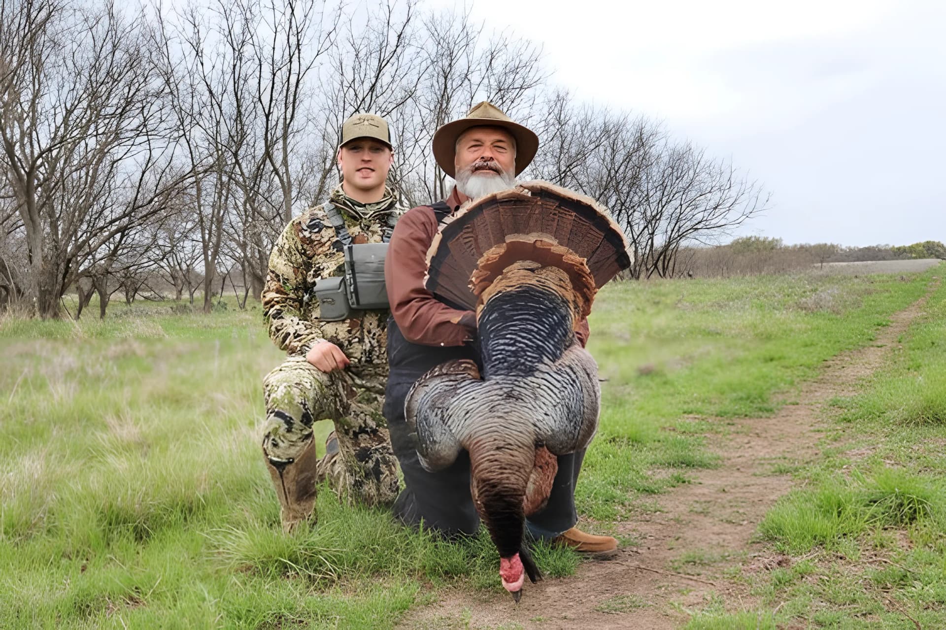 Father and son with a harvested wild turkey in a Texas pasture, continuing a multigenerational hunting tradition