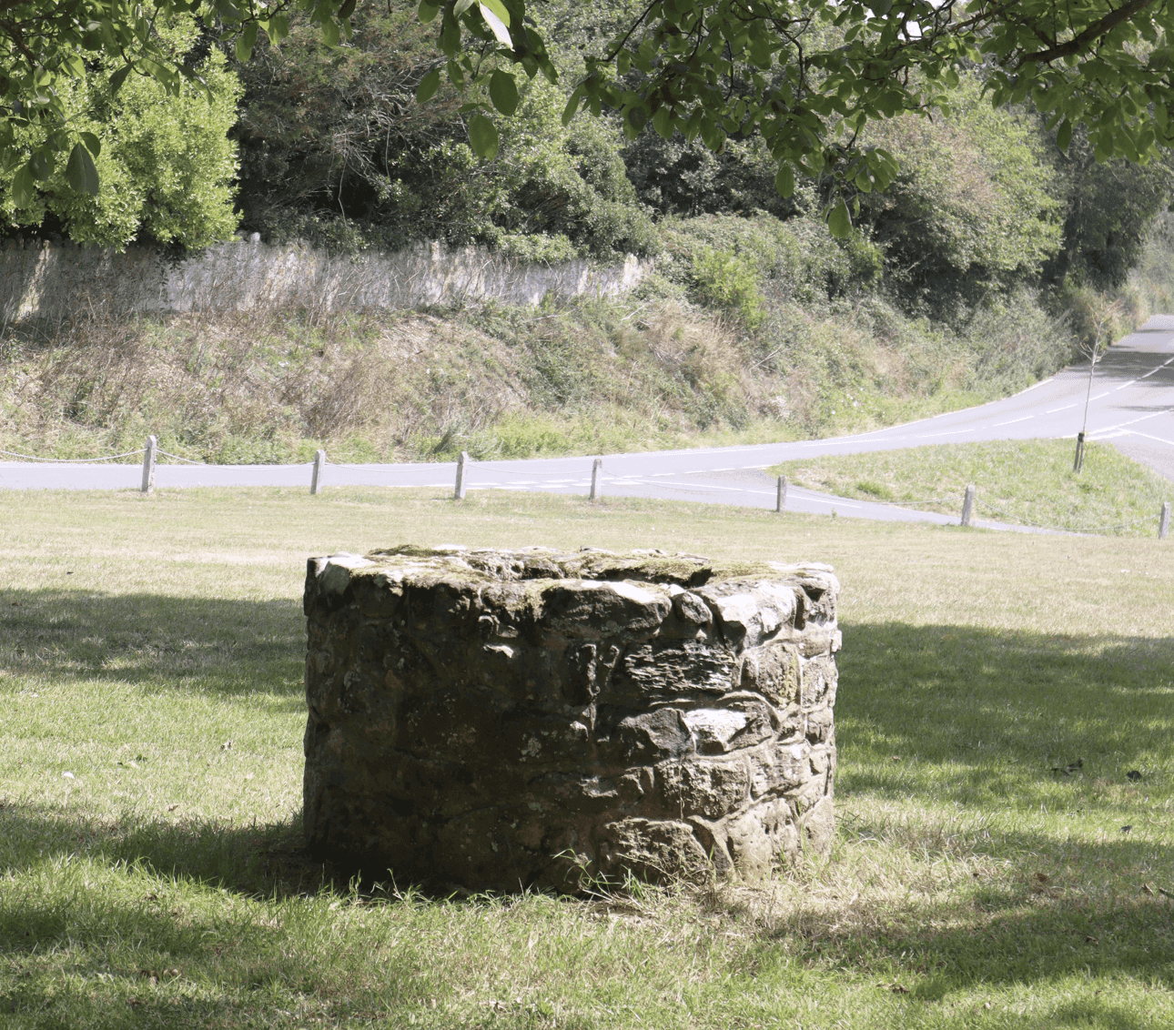 Historic stone water well in a grassy rural setting, representing traditional groundwater access on ranch properties.